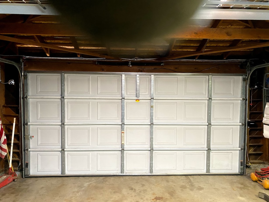 Closed white sectional garage door inside garage