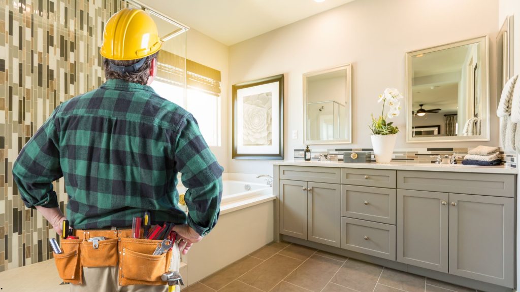 Contractor installing new tile and vanity during bathroom remodeling project